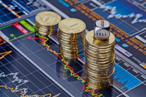 Downtrend stacks of golden coins and the dices cube with the wo